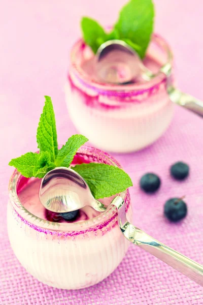 Zwei runde Gläser Joghurt-Dessert auf rosa Hintergrund, mit spo — Stockfoto