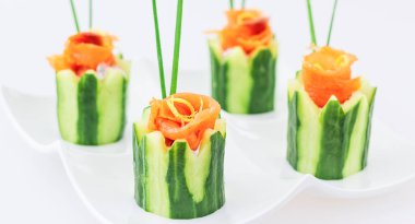 Beyaz arka planda füme somon, krem peynir ve salatalık aperatifi. 