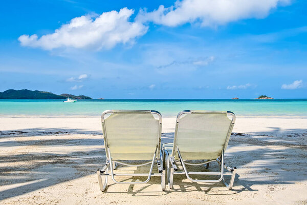 Two white beach chairs on tropical sandy beach, copy space