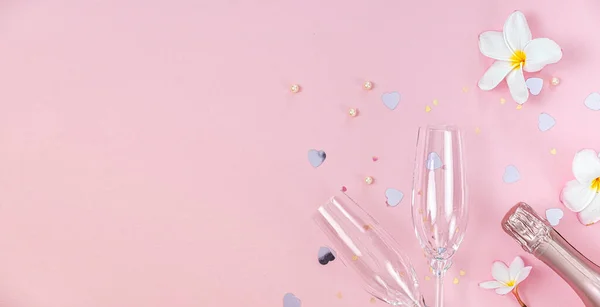 两个空的香槟酒杯和一瓶带有白色乳酪花和粉色背景的小心形装饰的香槟酒 复制空间 — 图库照片