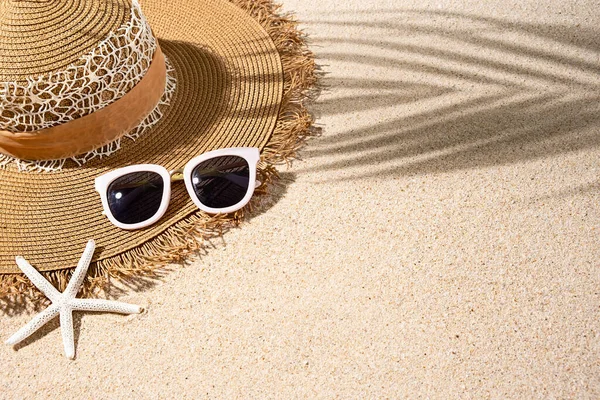 Large brown round summer heat, white sunglasses and starfish on nice beach sand, top view, copy space Royalty Free Stock Images