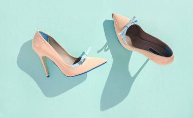 Açık yeşil zemin üzerinde bej renkli yüksek topuklu ayakkabılar, düz uzanmış.