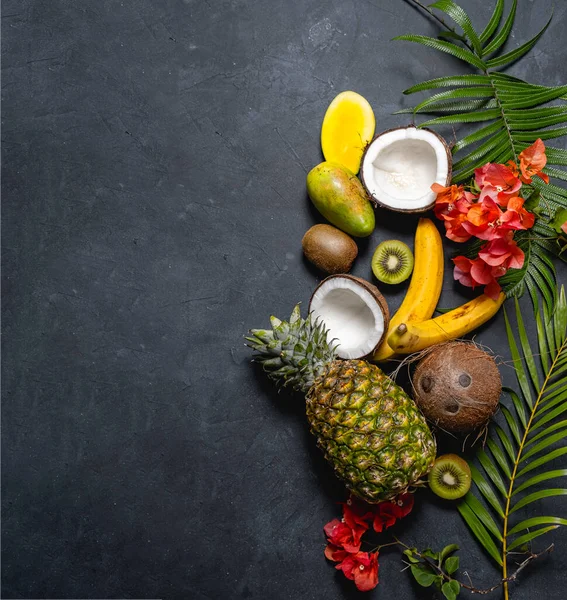 Misture frutas tropicais e flores no fundo escuro, vista superior. Alimentação saudável, Nutrição e conceito de dieta — Fotografia de Stock