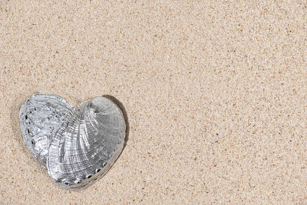 Top view of heart shape silver color seashell on sand background with copy space — Stock Photo, Image