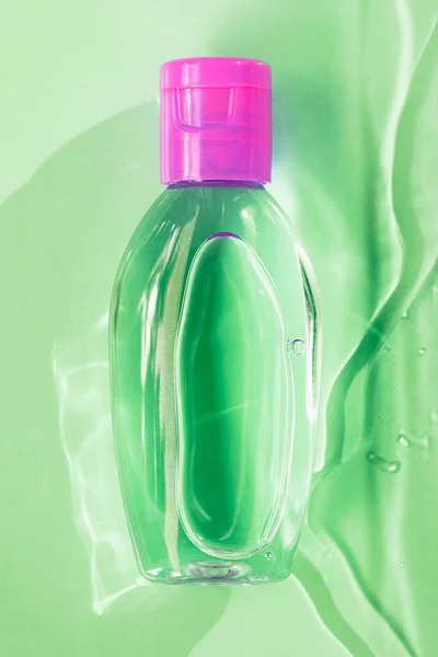 绿色透明小瓶，粉色杯子，绿色背景，水，顶部视图 — 图库照片