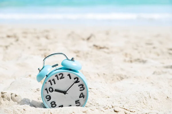 Relógio de alarme azul na praia de areia junto ao mar — Fotografia de Stock