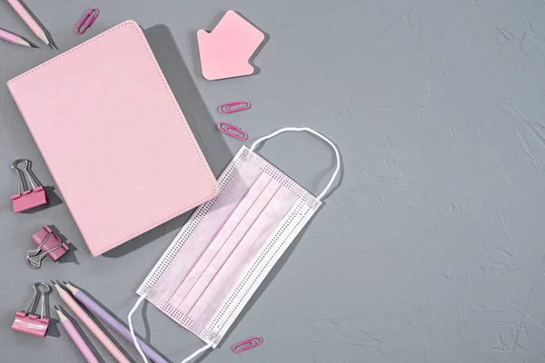 分门别类的粉色办公室和学校文具，灰色背景的办公用品和医疗面罩，顶视图 — 图库照片