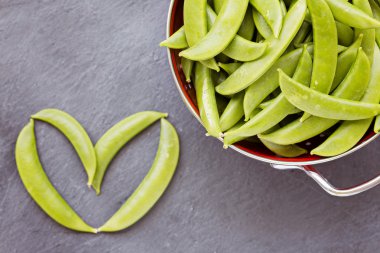 Kırmızı kevgir ve tek tek tarafında yeşil bezelye