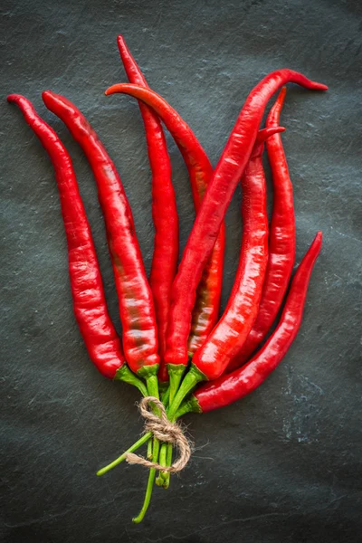 Pimientos rojos picantes sobre fondo de piedra gris oscuro, vista superior —  Fotos de Stock