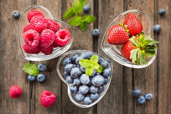 Mix of fresh berries in three  glass ramekins in shape of heart, — Stock Photo, Image