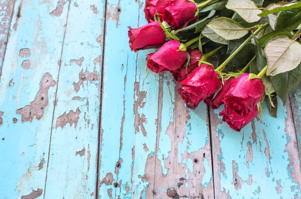 Rosas rojas sobre fondo de madera azul viejo — Foto de Stock