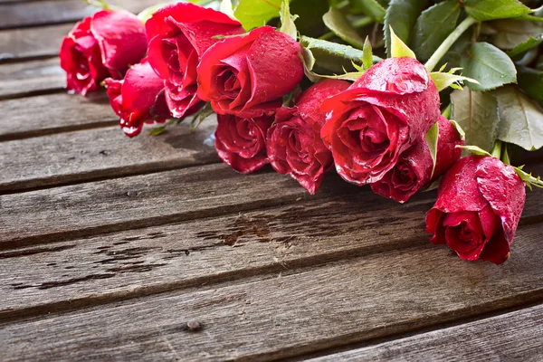 Rosas rojas sobre fondo de madera — Foto de Stock