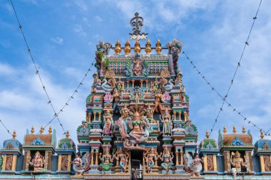 Sri Mahamariamman Tapınağı Vibrant Hindu tapınağı mavi gökyüzünün altında detaylı heykellerle süslenmiş.