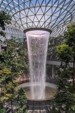Singapur, Singapur - 3 Ekim 2025 Changi Havaalanı Gri ve beyaz tonlu gösterişli mimari sergiler. Yer araçları mevcut ve bir merdiven bir uçak kapısına doğru gidiyor..