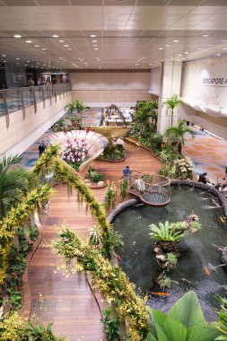 Singapur, Singapur - 3 Ekim 2025 Changi Havaalanı Gri ve beyaz tonlu gösterişli mimari sergiler. Yer araçları mevcut ve bir merdiven bir uçak kapısına doğru gidiyor..