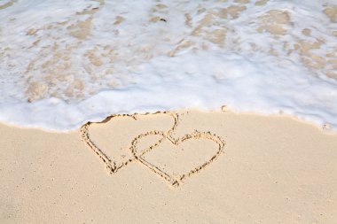 İki kalp plaj kum üzerine çizilmiş kalpleri silerek ihlalinden