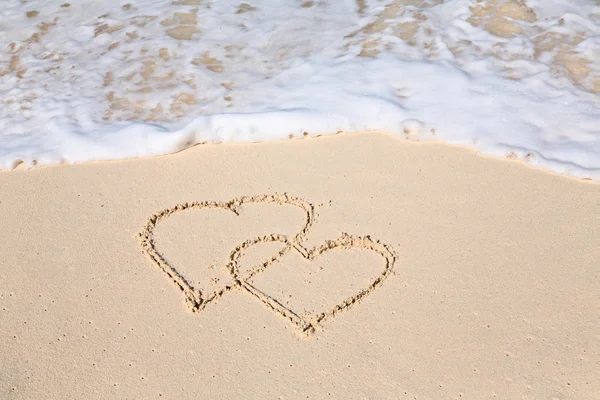 Dos corazones dibujados en la arena de la playa — Foto de Stock