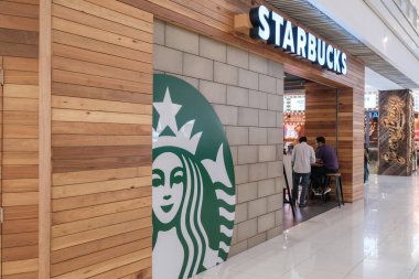 Penang, Malezya - 16 Ekim 2025 Starbucks logosu ahşap bir duvarda aydınlanıyor ve kahve markasının tipik yeşil ve beyaz ikonik tasarımı sergileniyor.