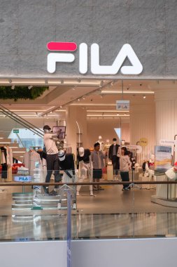 Singapur, Singapur - 3 Ekim 2025: Fila Changi Havaalanı mağazası son moda eğilimlerini keşfetmek isteyen müşterileri çeken şık kıyafetler, parlak ışıklandırma ve modern mimari ürünler sergiliyor.