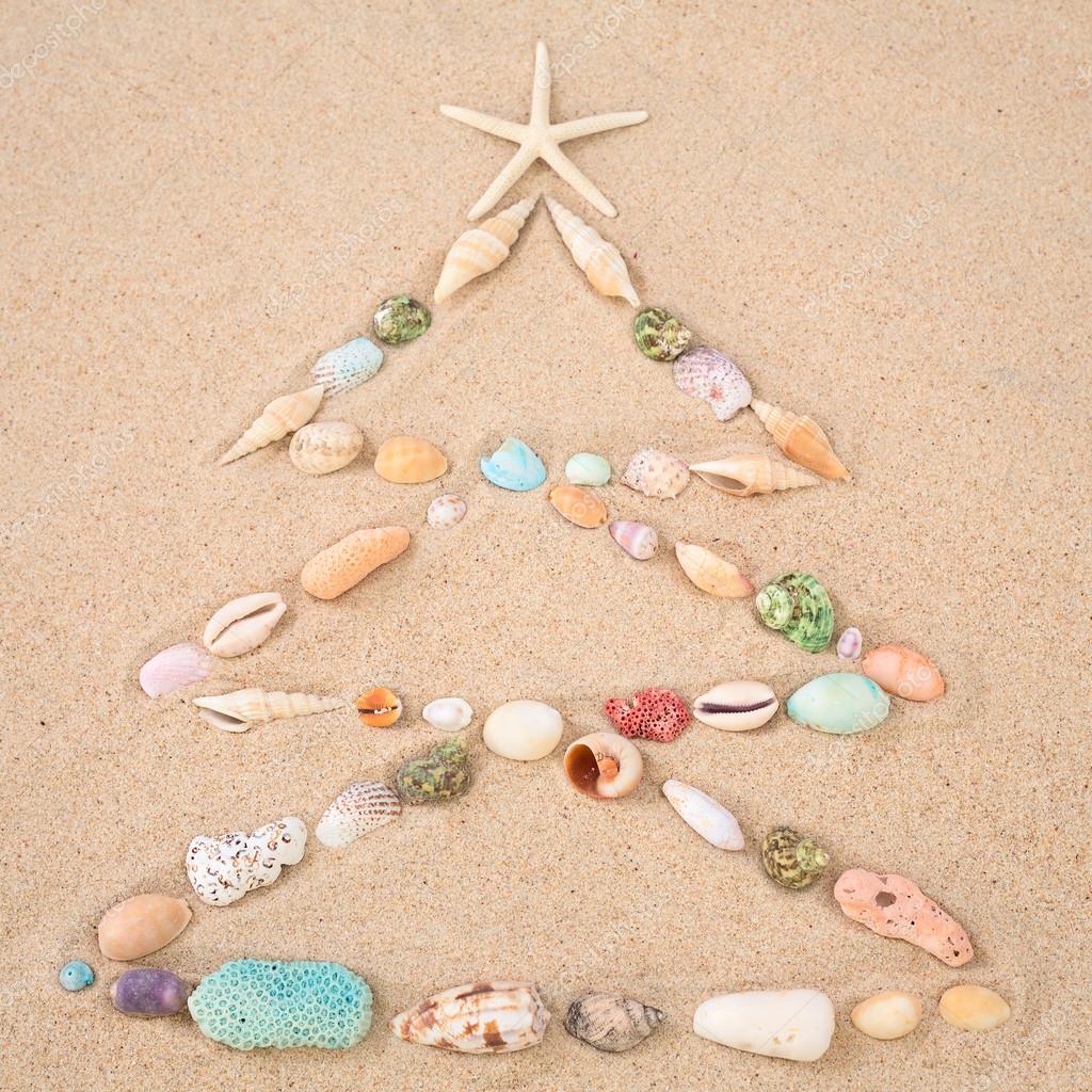 Beach Xmas concept, christmas tree on sand made out of sea shells Stock