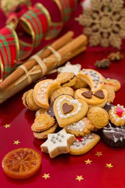 Biscotti di Natale, in diverse forme, con spezie, sfondo rosso festivo — Foto Stock