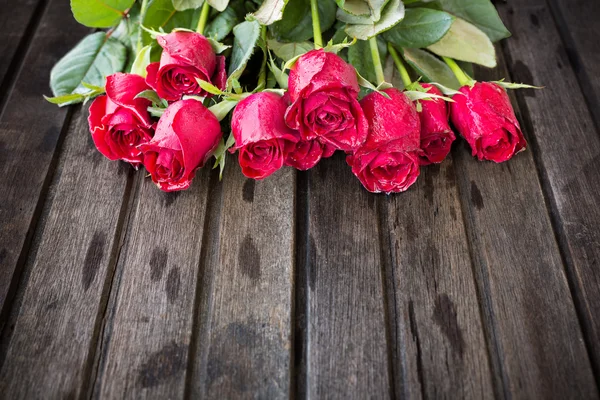Röda rosor på trä bakgrund — Stockfoto