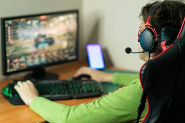 Genç tasarımcı, programcı, bilgi teknolojisi. Kulaklık takan genç bir adam bilgisayarda çalışıyor. Yazılım geliştiricisi. Oyuncu bilgisayar oyunları oynar. Genç adam teknolojide çalışıyor..