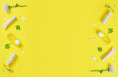 Sarı zemin üzerinde kozmetik ürünler ve çiçekler olan bahar afişi. Sarı arka planda kozmetik ürünler. Lüks dekoratif kozmetik seti.. 