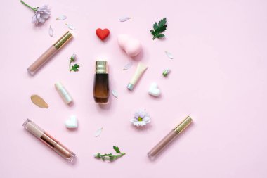 Kozmetik ürünleri ve pembe arka planda çiçekler olan bahar afişi. Pembe arka planda kozmetik ürünler. Lüks dekoratif kozmetik seti.. 