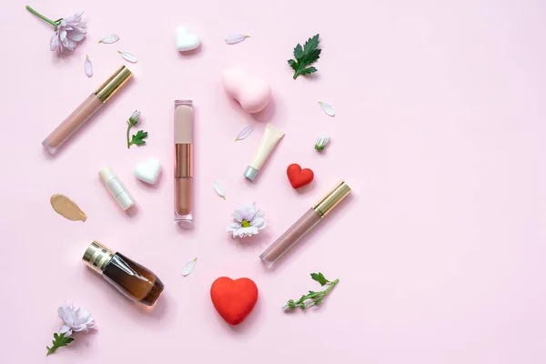 Kozmetik ürünleri ve pembe arka planda çiçekler olan bahar afişi. Pembe arka planda kozmetik ürünler. Lüks dekoratif kozmetik seti.. 