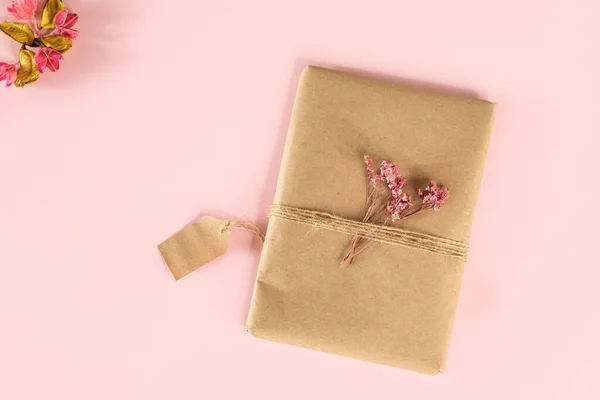 Kırbaçla bağlanmış ve kurutulmuş pembe çiçeklerle süslenmiş bir hediye. Hediye kutusu ya da Anneler Günü ya da Sevgililer Günü hediyesi. İlkbahar. 8 Mart.