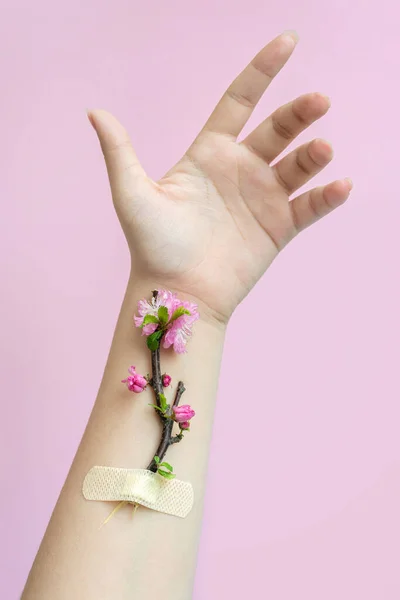 Kızın eline bantlanmış çiçekler. İnsanın doğayla bütünlüğü.