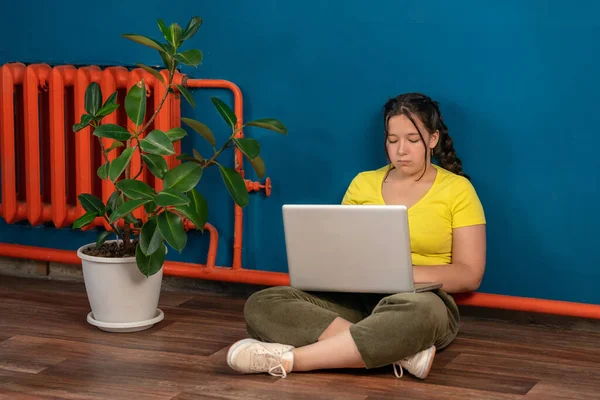 Kız dizüstü bilgisayarla yerde oturuyor ve işini yapıyor. çevrimiçi öğrenme kavramı.