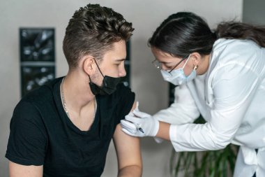 Genç bir adama omzundan enjeksiyon yapıldı. Koronavirüs aşısı. Koronavirüse karşı aşı. 