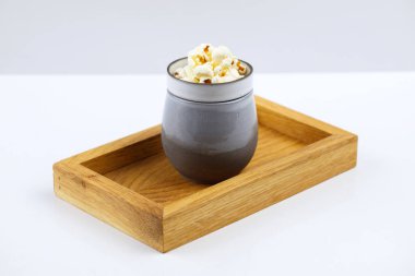 Ahşap tepside, içi ekşi çorba dolu kireç tepside, yanında sebze dolu bir peynir küpü beyaz arka planda.