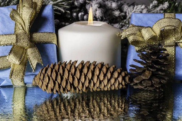 Blue Gifts Trimmed Gold Ribbon Pine Cones Burning Candle Reflecting — Stock Photo, Image