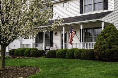 Beyaz koloni evi, siyah panjurlu beyaz çitli ve Amerikan bayrağı.