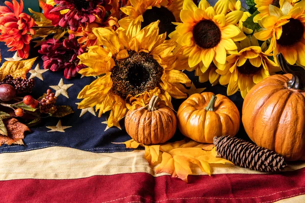 Orangefarbene Kürbisse Und Gelbe Sonnenblumen Auf Amerikanischer Flagge lizenzfreie Stockfotos