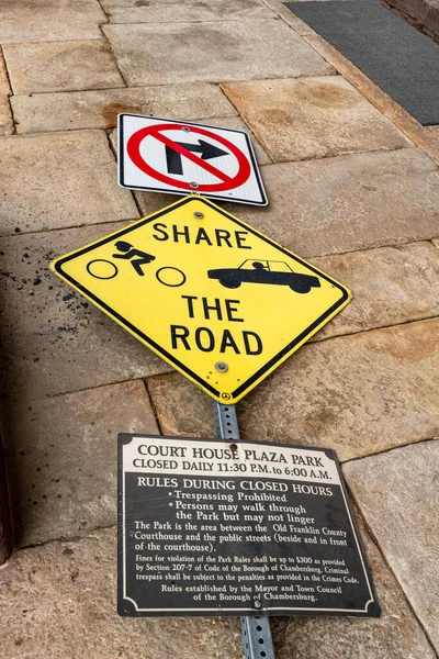 street sign telling people to share the road broken and lying on sidewalk