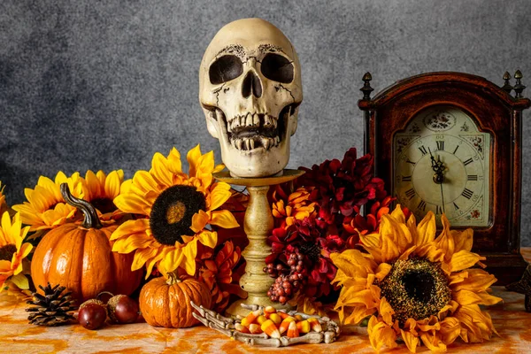カボチャのひまわりの古い時計と頭蓋骨でオレンジのキャンディーコーンで満たされた骨格の手 — ストック写真