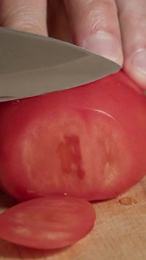 Bir domatesi yakın çekim bıçakla dilimlemek.