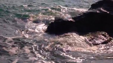 Deniz dalgaları taşa çarpar, fırtınalı deniz ve su üzerinde parlar. Karadeniz