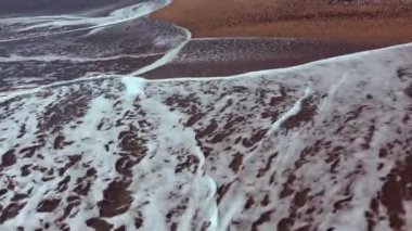 Beyaz köpüklü deniz dalgaları kumlu sahilde yuvarlanıyor. Güneşin sudaki yansıması. Karadeniz