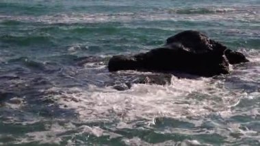 Deniz dalgaları taşa çarpar, fırtınalı deniz ve su üzerinde parlar. Karadeniz