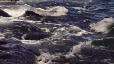 Deniz dalgaları taşa çarpar, fırtınalı deniz ve su üzerinde parlar. Karadeniz