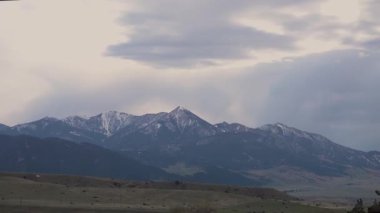 Karda dağlar, odunla kaplanmış. Dağların üzerinde kalın bulutlar. Montana, ABD