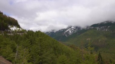 Karda dağlar, odunla kaplanmış. Dağların üzerinde kalın bulutlar. Montana, ABD