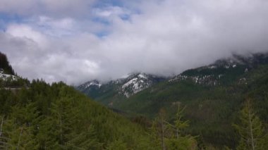 Karda dağlar, odunla kaplanmış. Dağların üzerinde kalın bulutlar. Montana, ABD