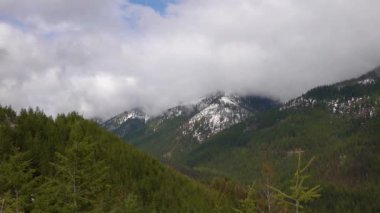 Karda dağlar, odunla kaplanmış. Dağların üzerinde kalın bulutlar. Montana, ABD