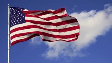 Mavi gökyüzüne ve beyaz bulutlara karşı dalgalanan Amerikan bayrağı. 